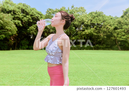 一位健康的女性在藍天下的天然草地上做完瑜伽後補充水分 127601493