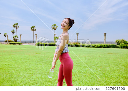 A healthy woman hydrating after yoga on natural grass under the blue sky A healthy woman hydrating after yoga on natural grass under the blue sky 127601500