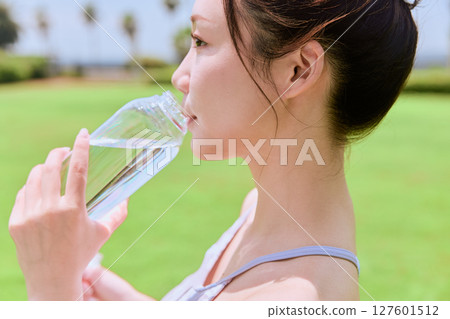 Healthy hydration after yoga on natural grass under blue sky Healthy hydration after yoga on natural grass under blue sky 127601512