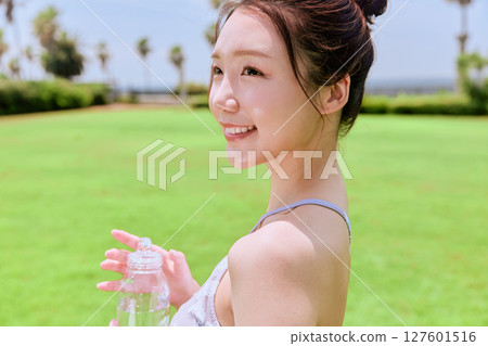 一位健康的女性在藍天下的天然草地上做完瑜伽後補充水分 127601516