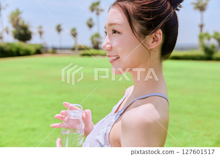 一位健康的女性在藍天下的天然草地上做完瑜伽後補充水分 127601517