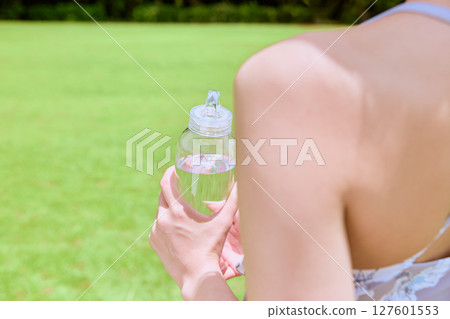 一位健康的女性在藍天下的天然草地上做完瑜伽後補充水分 127601553