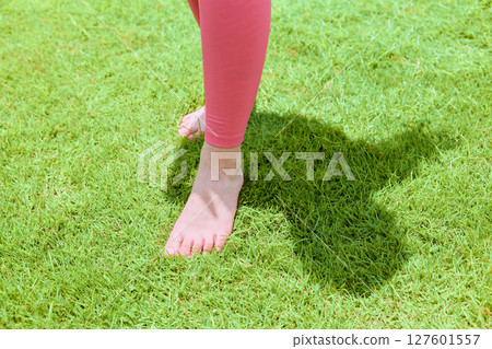 A woman doing yoga and pilates on natural grass in a resort atmosphere 127601557