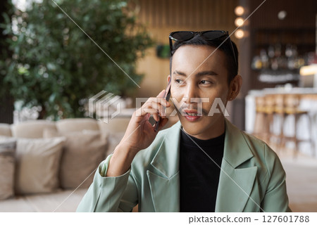 Portrait of nonbinary genderfluid young Asian gay businessman using phone in cafe 127601788