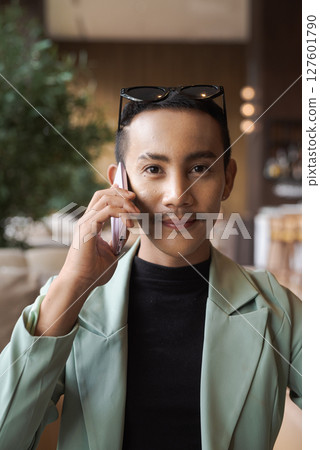 Portrait of nonbinary genderfluid young Asian gay businessman using phone in cafe 127601790
