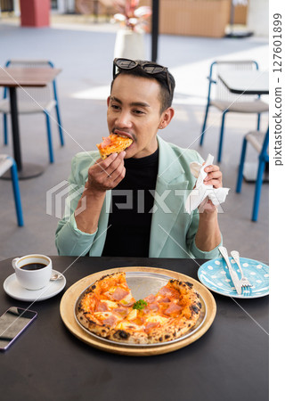 Portrait of nonbinary genderfluid young Asian gay man eating pizza ourdoors Portrait of nonbinary genderfluid young Asian gay man eating pizza ourdoors 127601899
