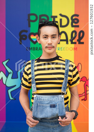 Portrait of nonbinary genderfluid young Asian gay man against pride flag background Portrait of nonbinary genderfluid young Asian gay man against pride flag background 127601932