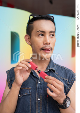 Portrait of confident non binary gay man holding lipstick Portrait of confident non binary gay man holding lipstick 127601980