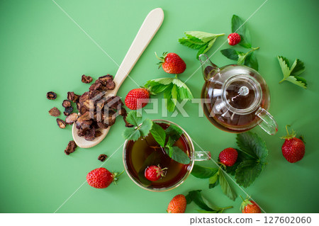 Bright strawberry tea in transparent glassware on a green background Bright strawberry tea in transparent glassware on a green background 127602060
