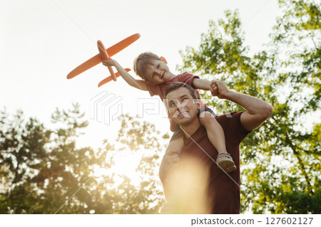 Father and son playing with toy airplane outdoors 127602127