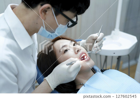 Dentist is working on a woman's teeth 127602545