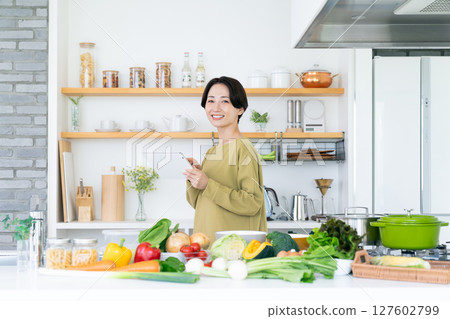 Middle-aged housewife with tablet in kitchen Middle-aged housewife with tablet in kitchen 127602799