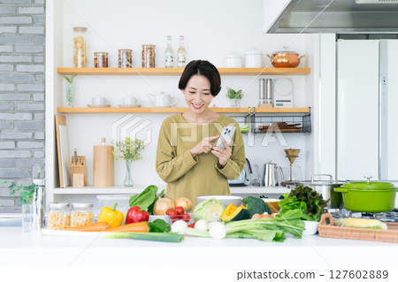 中年家庭主婦在廚房拿著智慧型手機 127602889