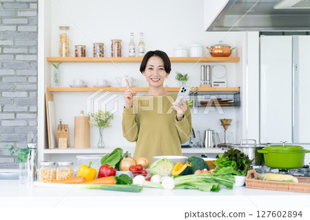 中年家庭主婦在廚房拿著智慧型手機 127602894