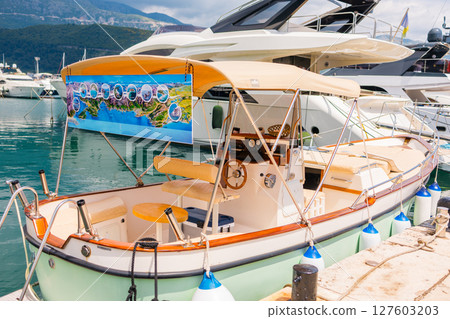 Small boats floating in marina with mountain backdrop. Coastal lifestyle, nautical tourism, and scenic summer destination. 127603203