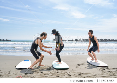 年輕人和教練在沙灘上體驗衝浪 衝浪學校圖片 127603262