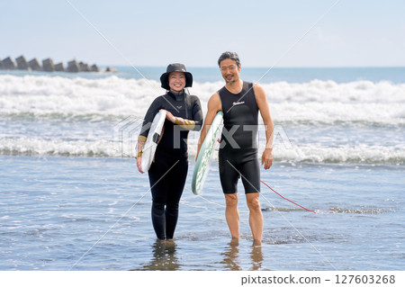 Smiling surfers standing with their surfboards 127603268