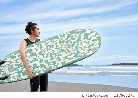 一名年輕男子試圖在海灘上衝浪的肖像 127603273