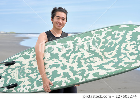 拿著衝浪板的微笑的年輕人 127603274