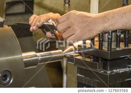 Close up scene the machine operator measuring dimension of turning parts by Vernier caliper. Close up scene the machine operator measuring dimension of turning parts by Vernier caliper. 127603568
