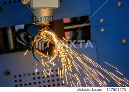 Close up scene the fiber laser cutting machine cut the stainless steel tube with sparkling light. 127603570