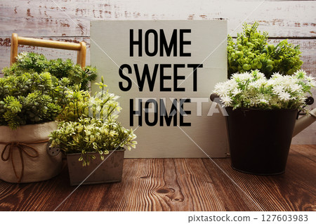 Home Sweet Home text with alarm clock on wooden background 127603983