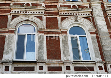 Architectural detail of vintage building featuring arched windows and textured brick facade Architectural detail of vintage building featuring arched windows and textured brick facade 127604311