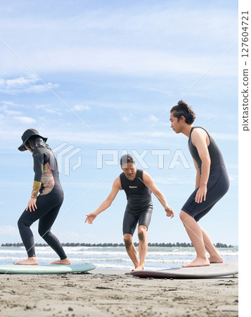 Young people and instructors experiencing surfing on the beach Surfing school image Young people and instructors experiencing surfing on the beach Surfing school image 127604721