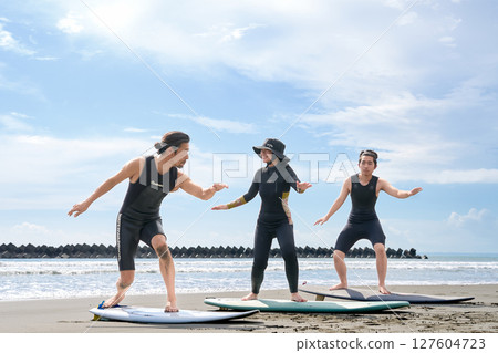 年輕人和教練在沙灘上體驗衝浪 衝浪學校圖片 127604723