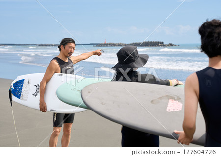 Instructor and participants checking the ocean conditions before surfing 127604726