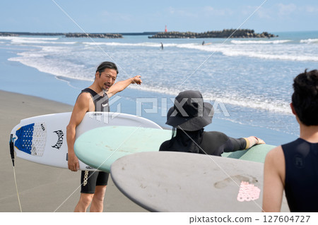 Instructor and participants checking the ocean conditions before surfing 127604727