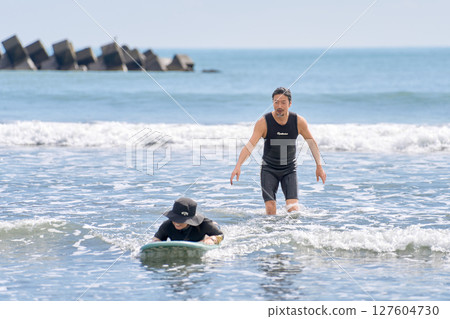 一名女子嘗試衝浪，教練為她加油 127604730