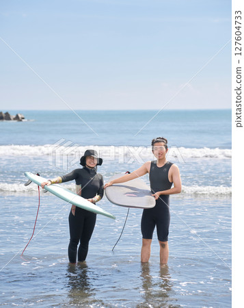 一名女子和一名年輕男子在海上衝浪的兩張照片 127604733