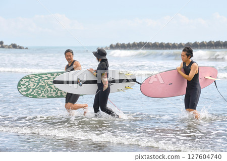 衝浪後，三名男子和女子微笑著返回海灘 127604740