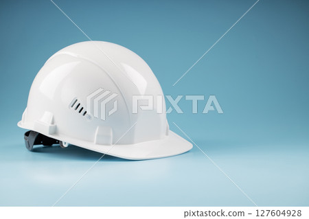 White safety helmet on a blue background with free space White safety helmet on a blue background with free space 127604928