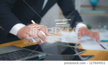 License agreement, featuring digital checkmarks and signatures. Symbolizes efficient online contract management and modern legal agreements. Businessman uses a stylus to interact with documents. License agreement, featuring digital checkmarks and signatures. Symbolizes efficient online contract management and modern legal agreements. Businessman uses a stylus to interact with documents. 127604952