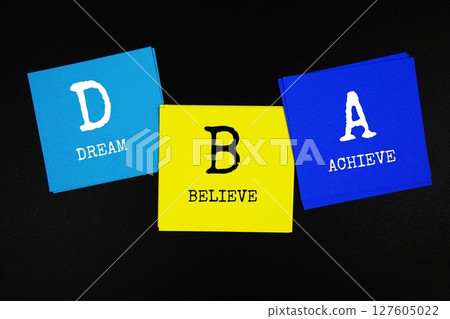 DBA - Dream Believe Achieve acronym text on sticky note on black background DBA - Dream Believe Achieve acronym text on sticky note on black background 127605022