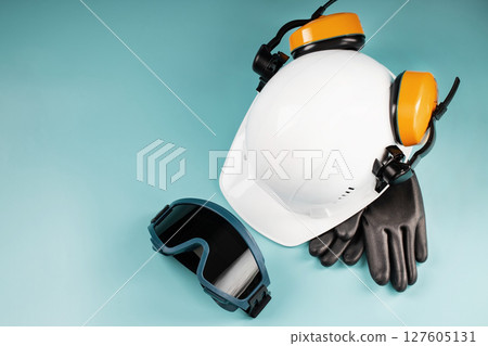Yellow headphones with a white helmet and dark welding glasses on a blue background 127605131