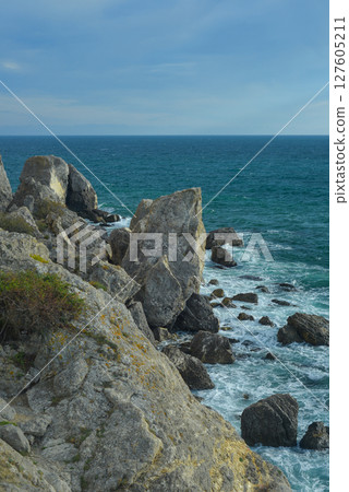 Waves of the Black Sea crash on a rocky shore on a sunny day in Crimea. Waves of the Black Sea crash on a rocky shore on a sunny day in Crimea. 127605211