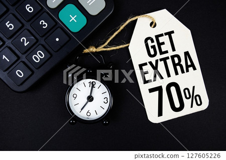 Get Extra 70% text on price tag with alarm clock and calculator on black background Get Extra 70% text on price tag with alarm clock and calculator on black background 127605226
