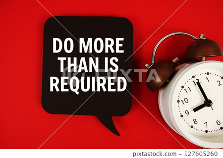 Do More Than Is Required text on speech bubble with alarm clock on red background 127605260
