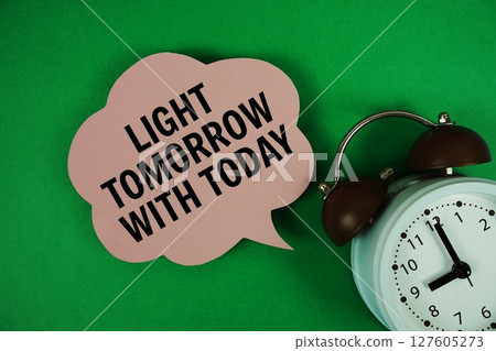Light Tomorrow With Today text on speech bubble with alarm clock on green background Light Tomorrow With Today text on speech bubble with alarm clock on green background 127605273