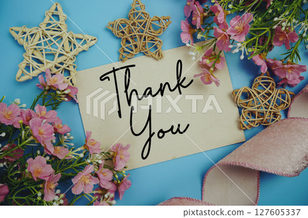 Thank You text on paper card with fabric ribbon and rattan star decorations on blue background 127605337