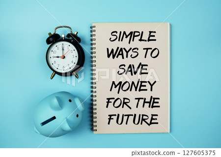 Simple Ways To Save Money For The Future text on notebook paper and piggy bank and alarm clock on blue background Simple Ways To Save Money For The Future text on notebook paper and piggy bank and alarm clock on blue background 127605375