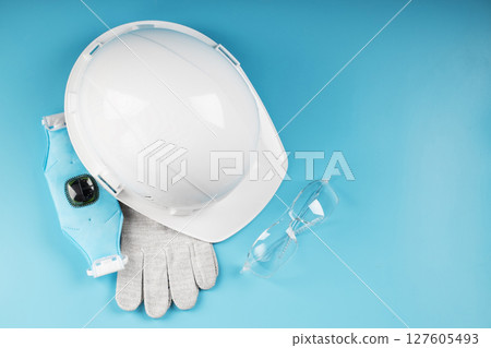 White construction worker safety helmet with personal protective equipment on blue background 127605493