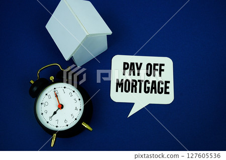 Pay Off Mortgage text with alarm clock and house model top view on blue background 127605536