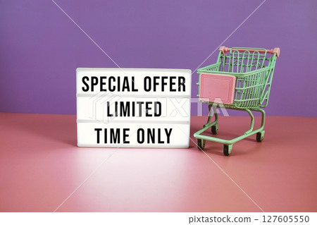 Special Offer Limited Time Only text on LED lightbox with trolley shopping cart on pink and purple geometric background 127605550