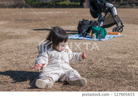[One-year-old child sitting and playing on the grass at Sagamihara Municipal Asamizo Park] 127605655