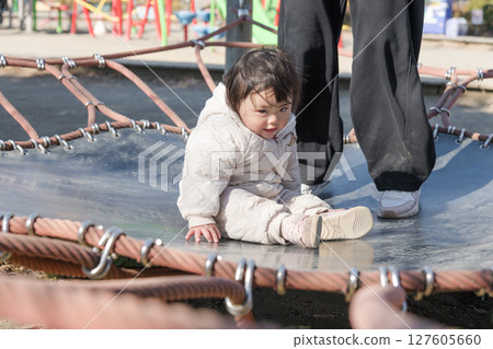 [A one-year-old child playing with his mother on the trampoline in the children's playground at Sagamihara City Asamizo Park] 127605660