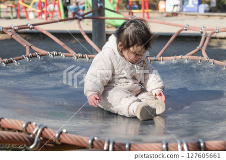 [A one-year-old child playing on a trampoline in the children's playground at Sagamihara City Asamizo Park] 127605661